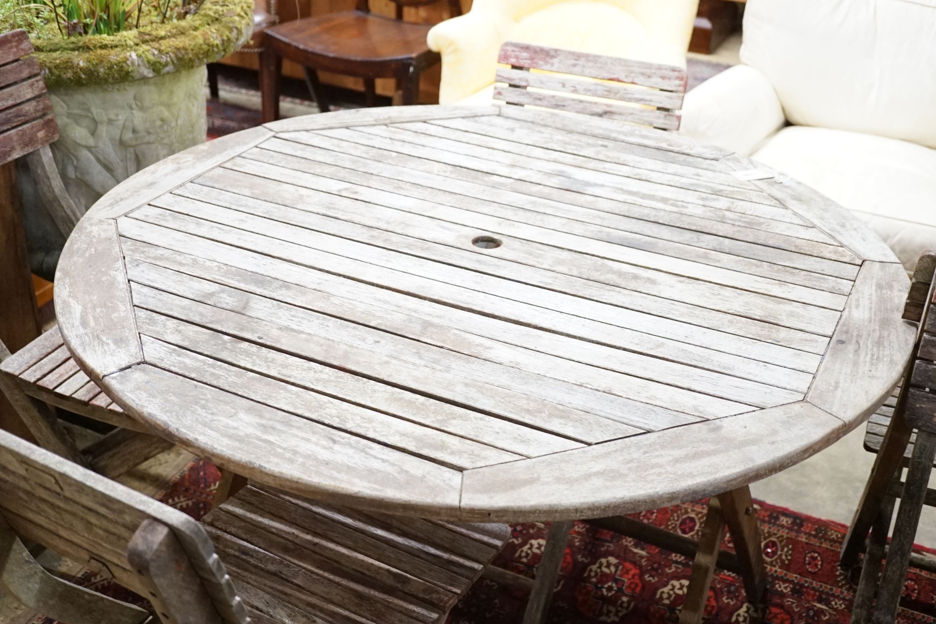 A weathered teak circular folding garden table and five folding chairs